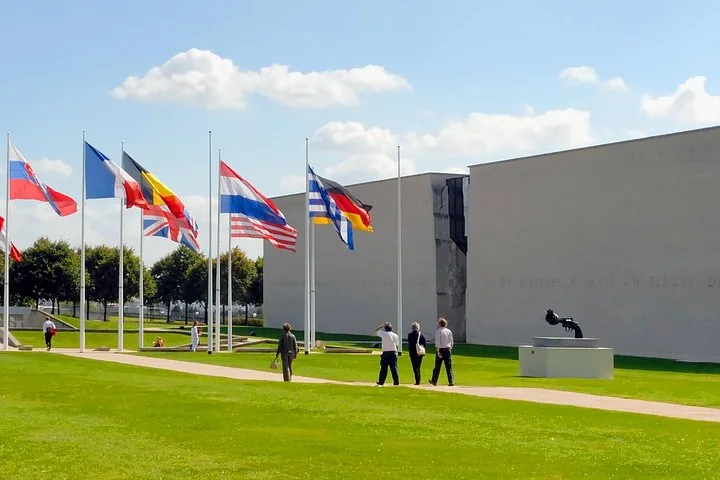 Flags of many nations flying on a lawn in front of a modern stone museum building