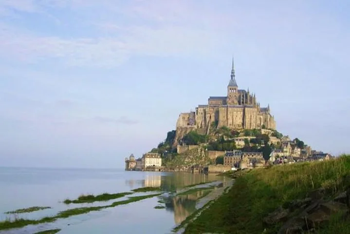 A tidal island crowned by an abbey, reflected in shallow water at low tide