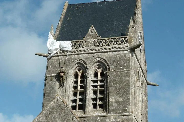 A paratrooper figure hanging by his parachute from a stone church steeple